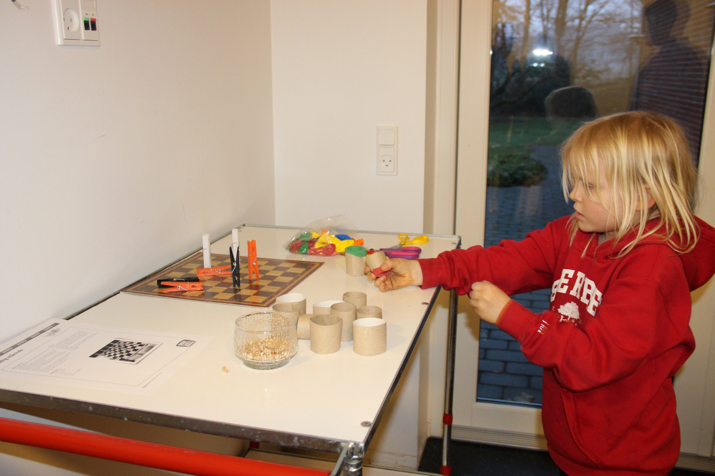Barn laver kunsthåndværk med paprør ved et bord.
