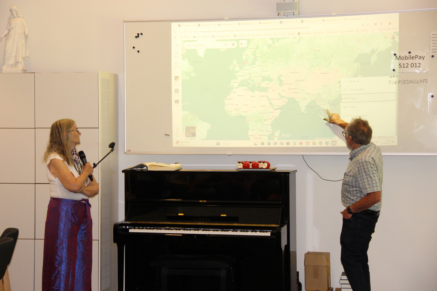 To voksne præsenterer ved hjælp af et projiceret kort og whiteboard.