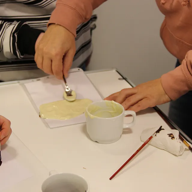 Hænder spreder smeltet hvid chokolade, maler et design i nærheden.