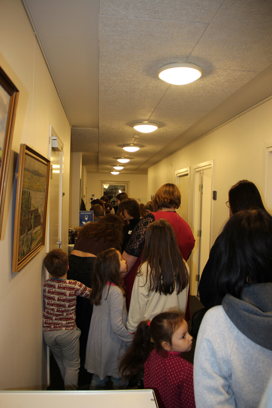 Folk, inklusiv børn, venter i kø i en gang.