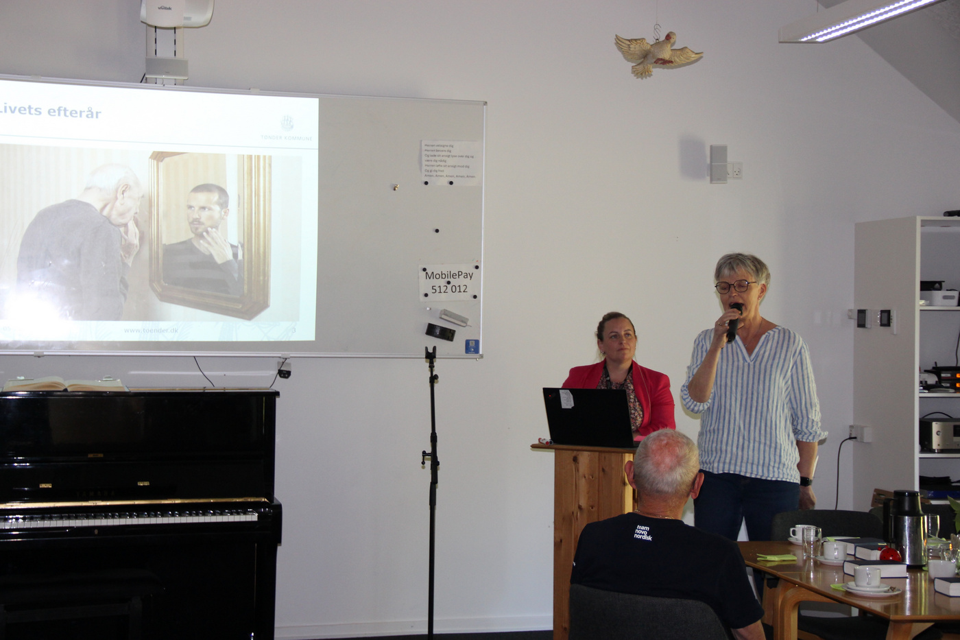 To kvinder taler ved en præsentation med et projiceret billede.