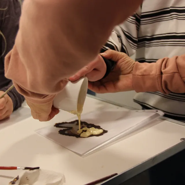 Hænder hælder smeltet chokolade på en designskabelon.