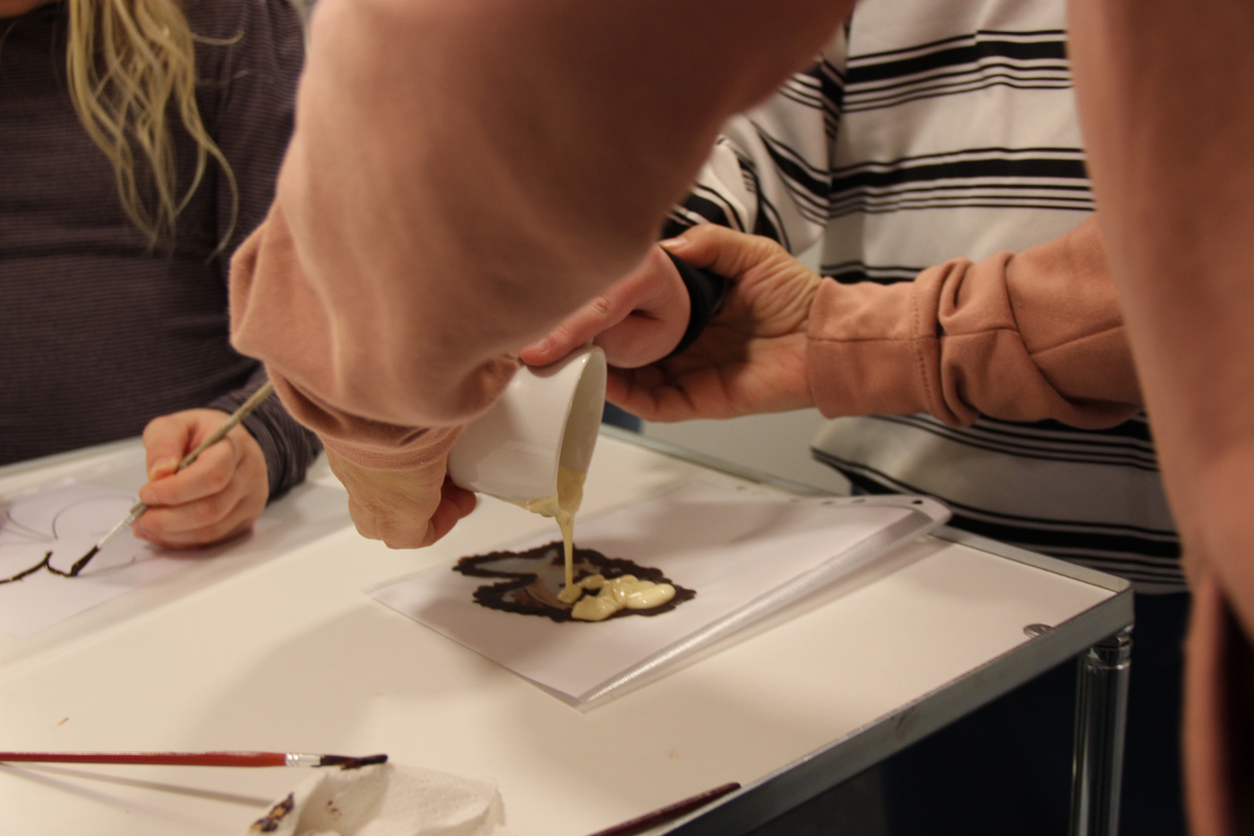 Hænder hælder smeltet chokolade på en designskabelon.