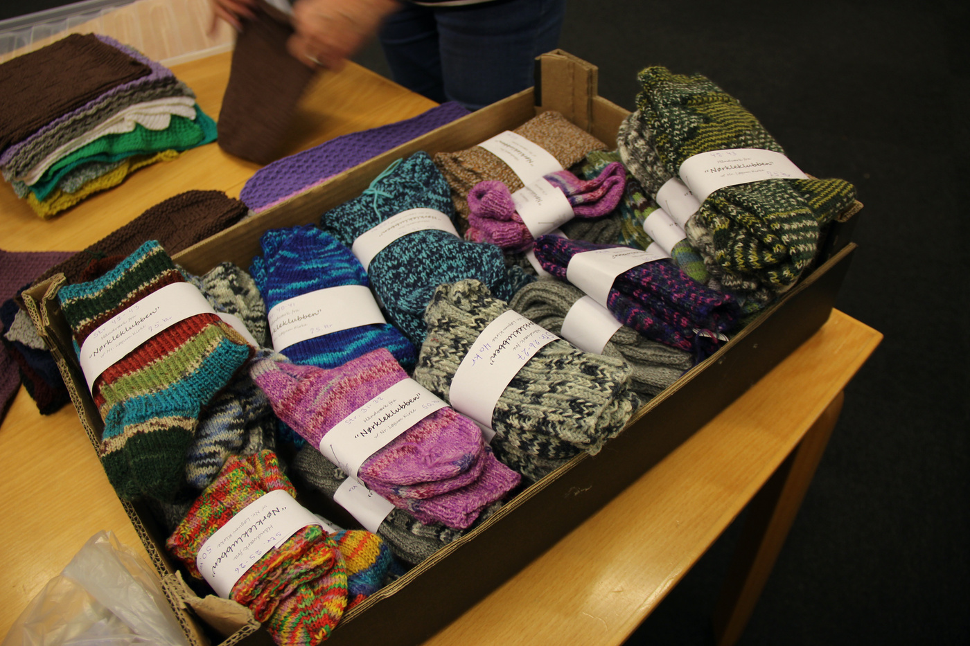 Kasse fyldt med pænt rullede, farverige strikkede sokker.
