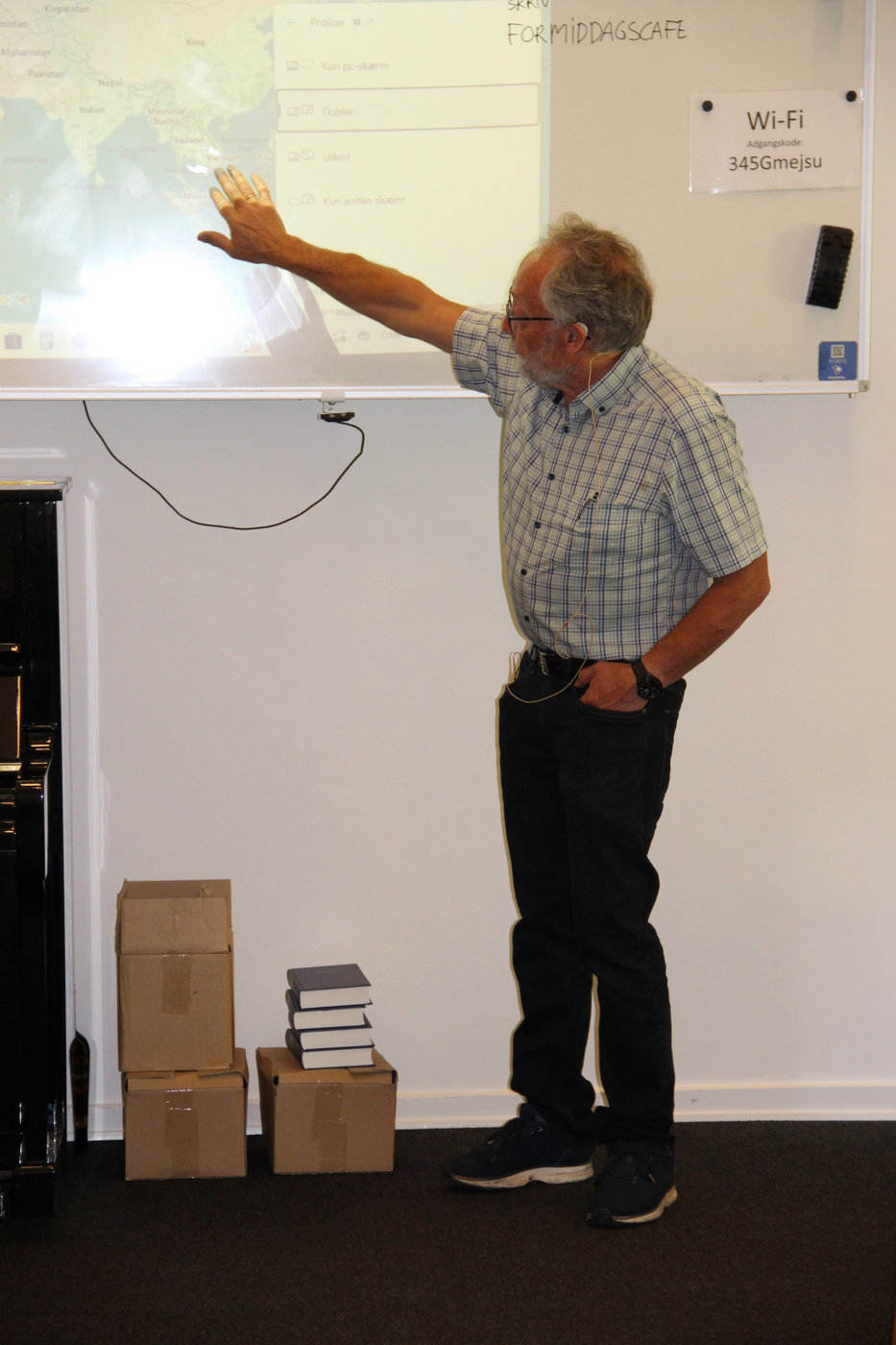 Mand peger på et kort projiceret på en whiteboardtavle.