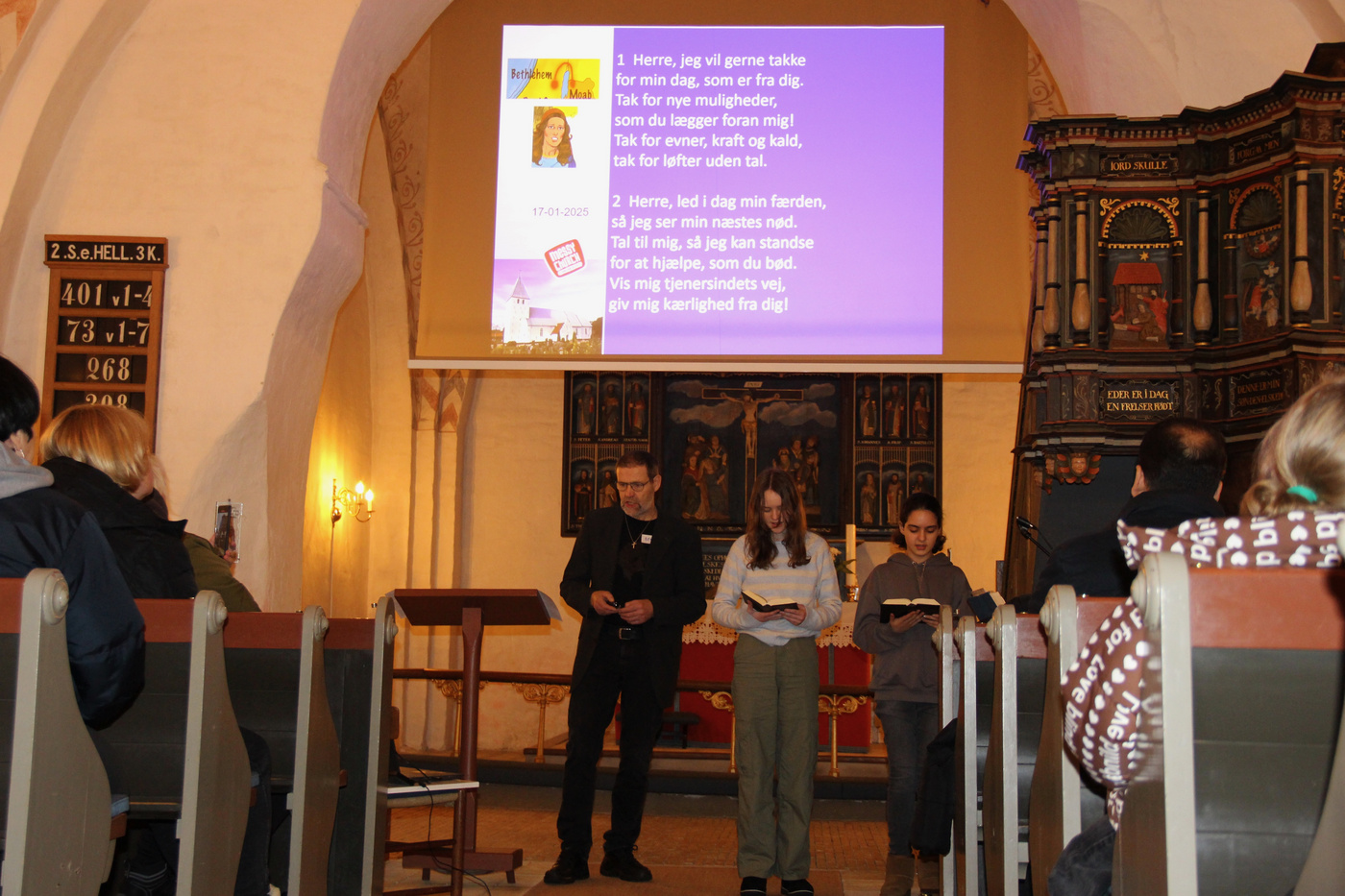 Folk samlet i kirken, med synlige projicerede salmetekster.