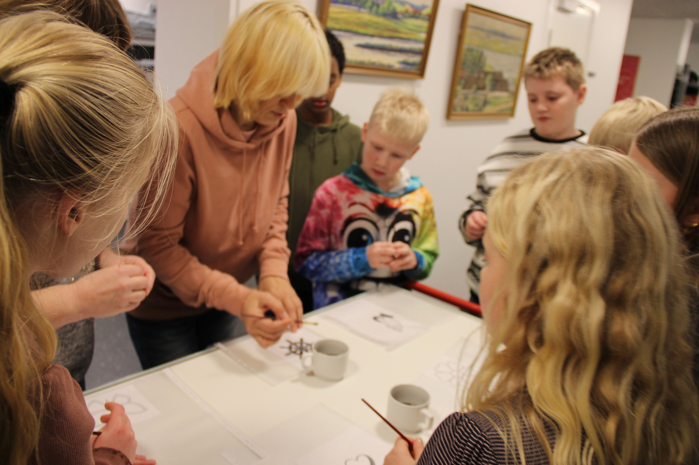  Voksne og børn samlet omkring et bord, engageret i en kreativ aktivitet.