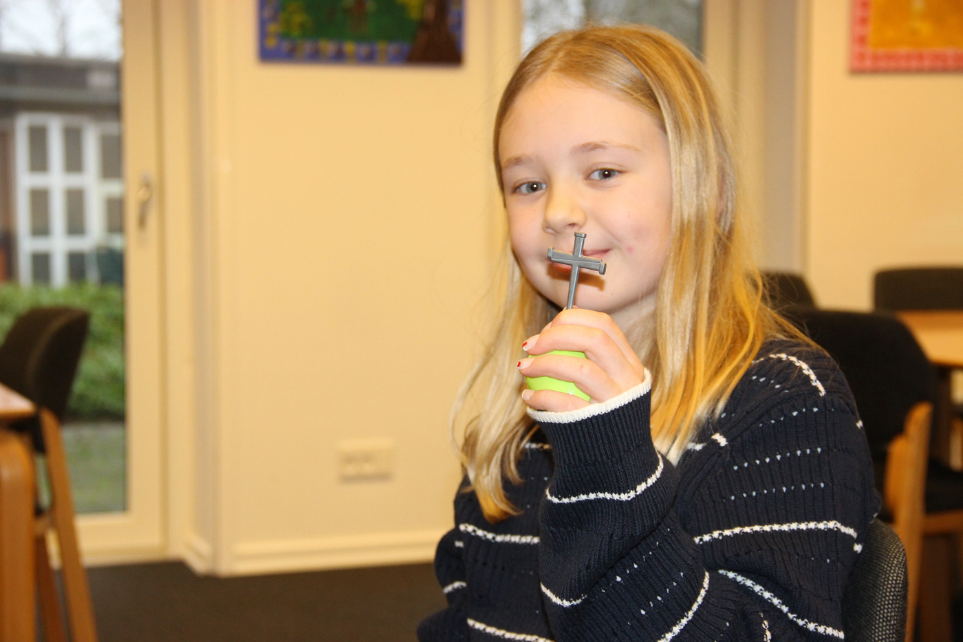 Pige smiler, holder et lille kors og et grønt æg.