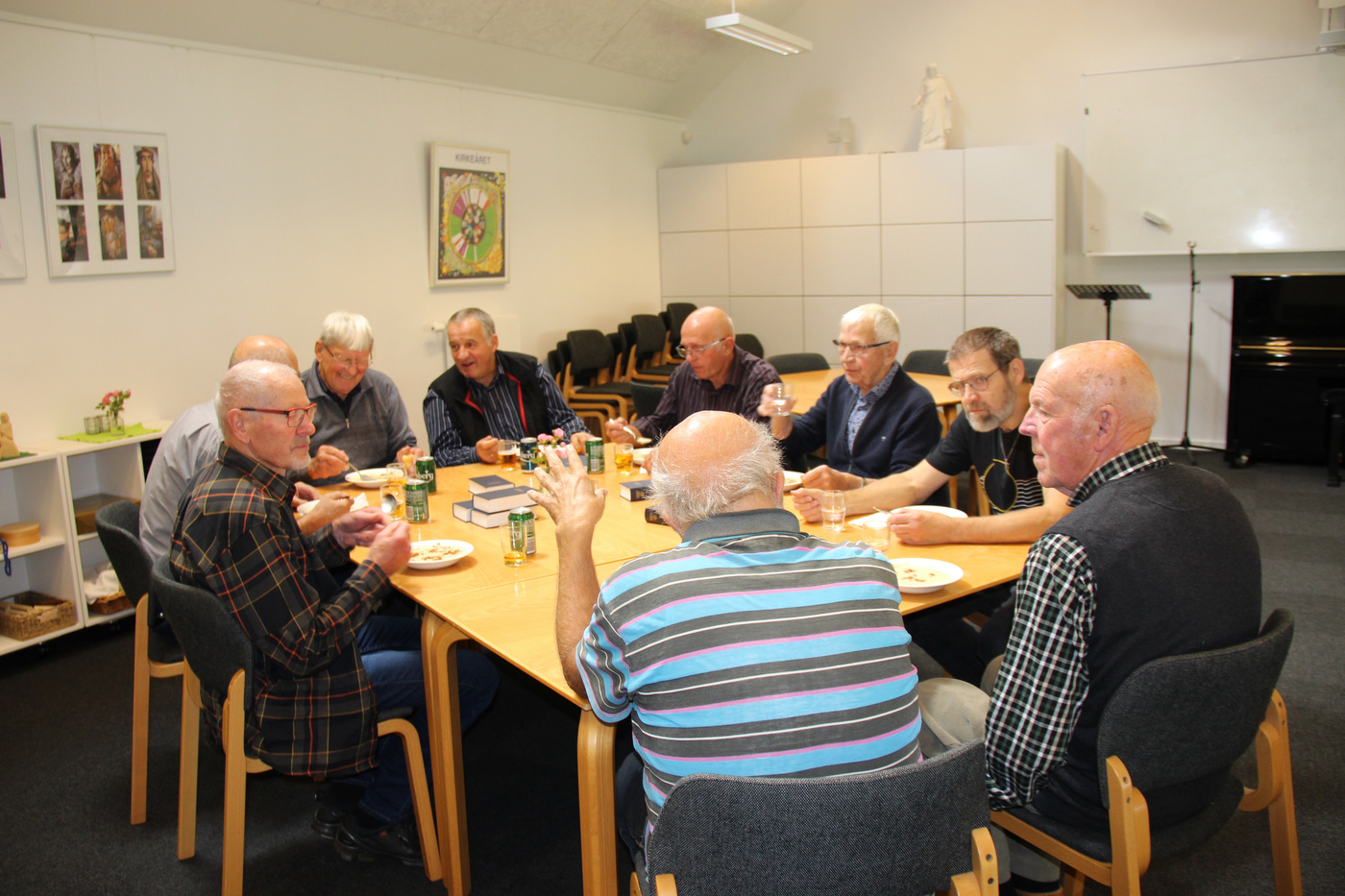 Ældre mænd samlet omkring et bord, nyder fællesskab og samtale.