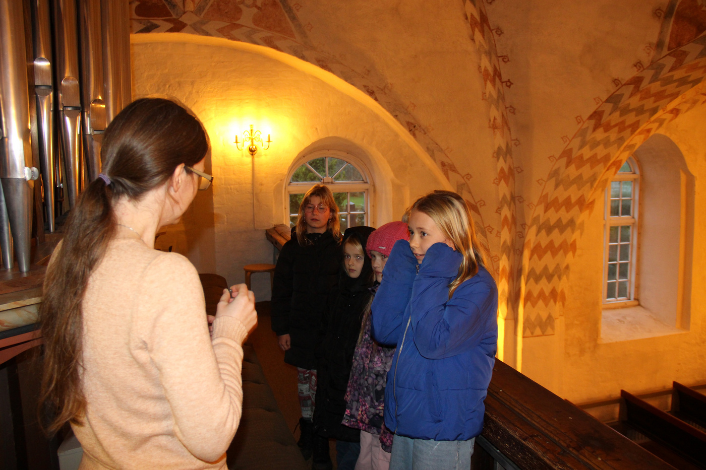  Kvinde taler med børn i kirken, et dækker sine ører.