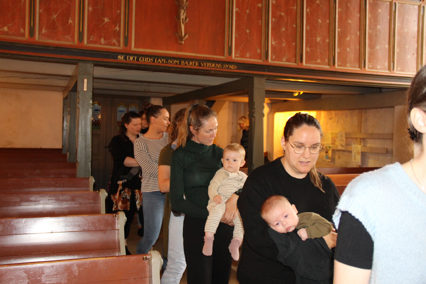 Kvinder med babyer går ned ad kirkens midtergang.
