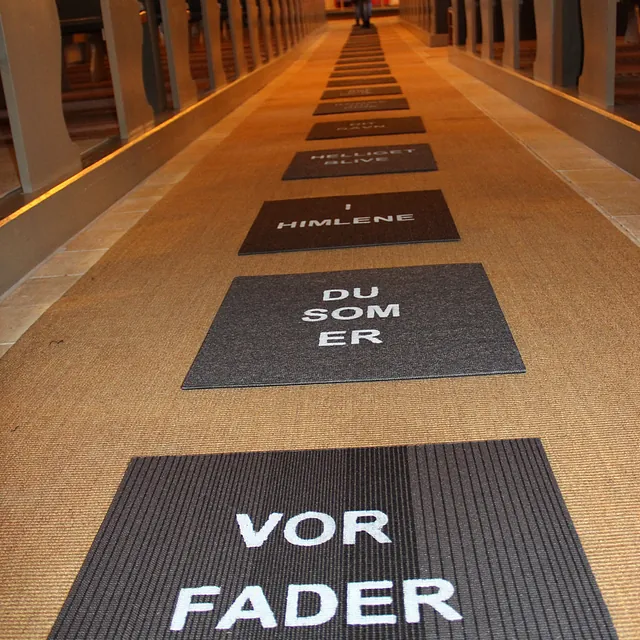 Tekst på gulvmåtter i en kirkegang: 