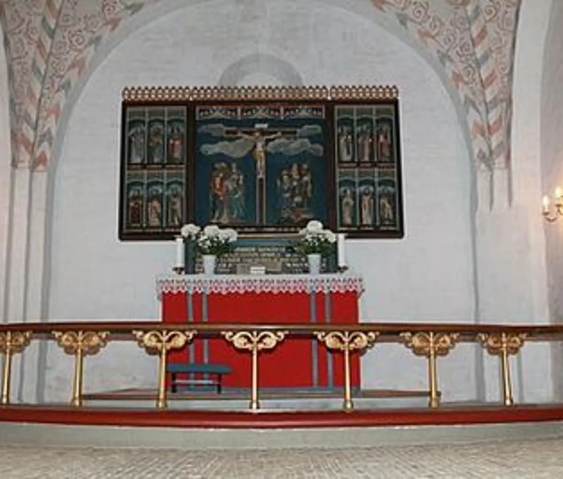 Kirkealter med malet altertavle og alterring, under mønstret bue.