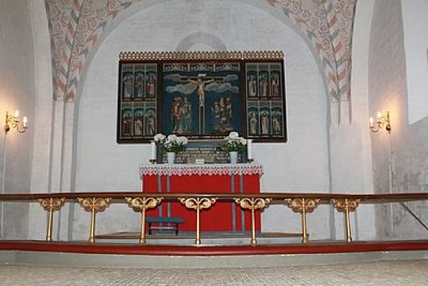 Kirkealter med malet altertavle og alterring, under mønstret bue.