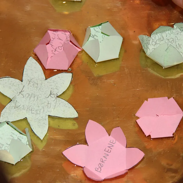 Flydende papirblomster og geometriske former med tekst.