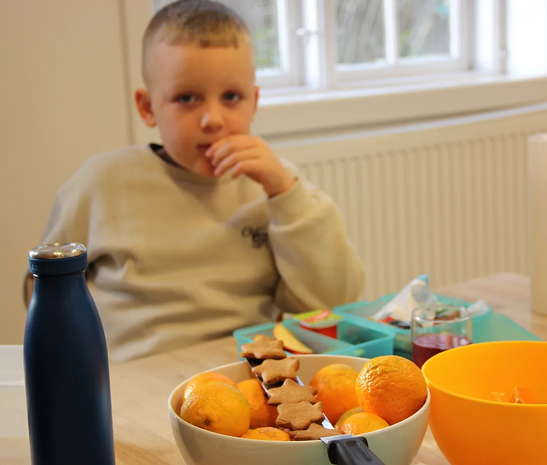 Dreng spiser ved bord med frugt og stjerneformede småkager.