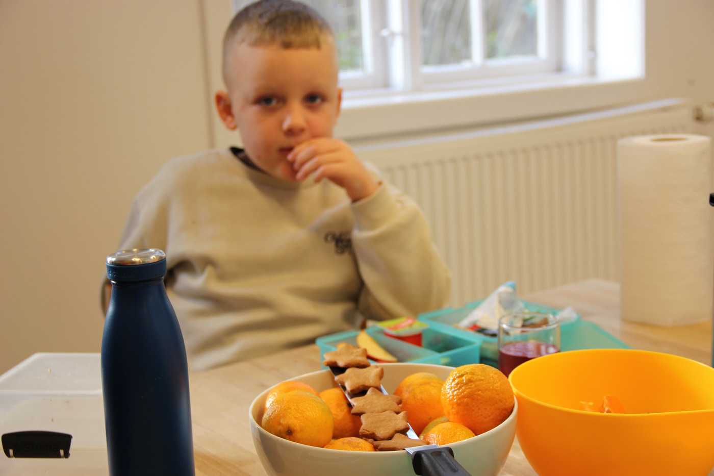 Dreng spiser ved bord med frugt og stjerneformede småkager.