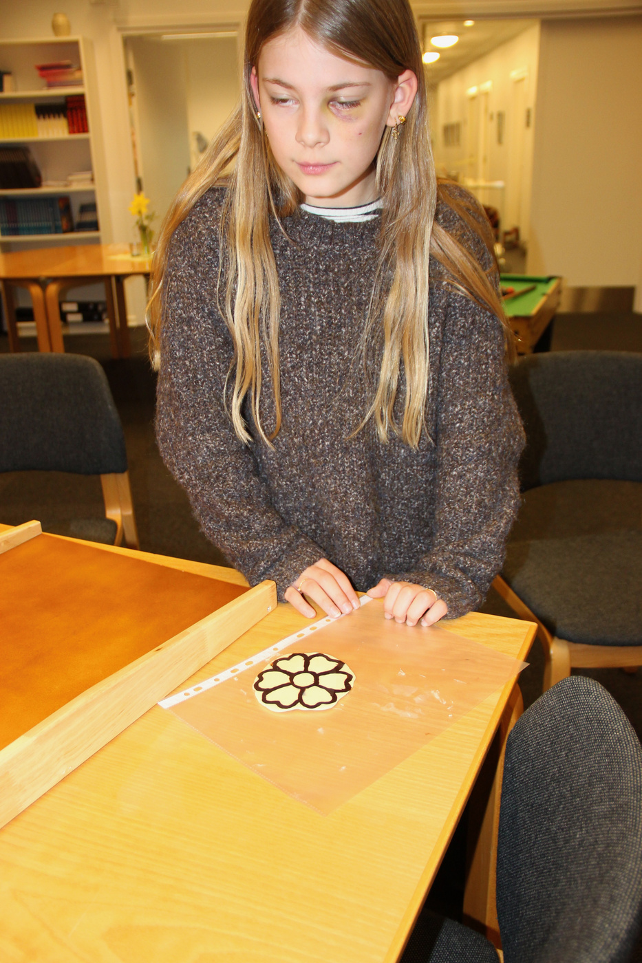 Pige koncentrerer sig om at pynte en blomsterformet småkage.