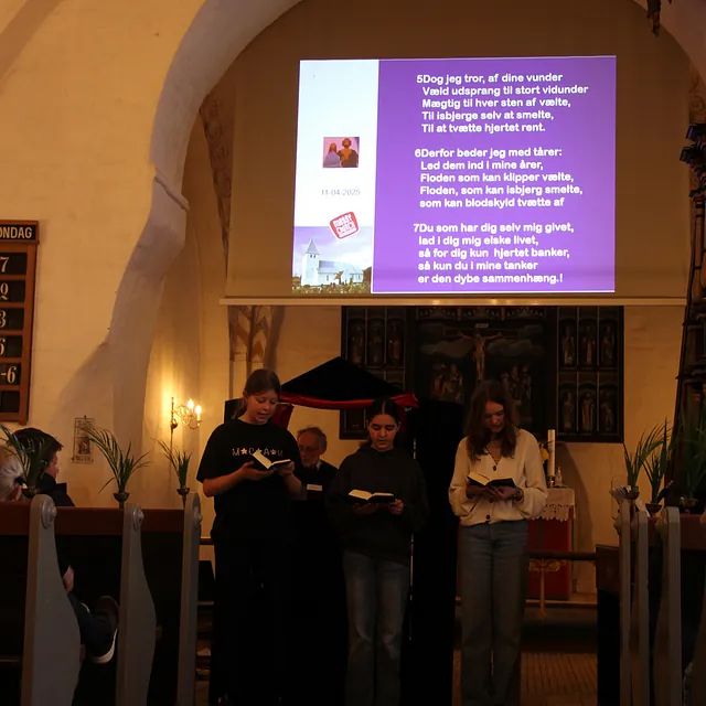 Tre unge læser fra bøger i en kirke med projicerede salmer.