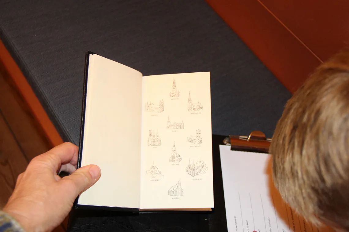 Person holder bog åben til side med kirkeillustrationer.