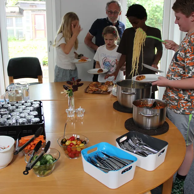 Folk tager pasta, salat og mad fra et buffetbord.