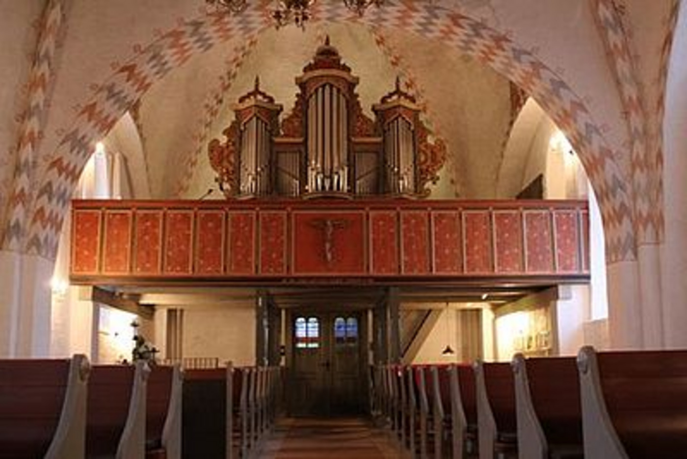 Kirkeinteriør med træbænke mod et stort pibeorgel.