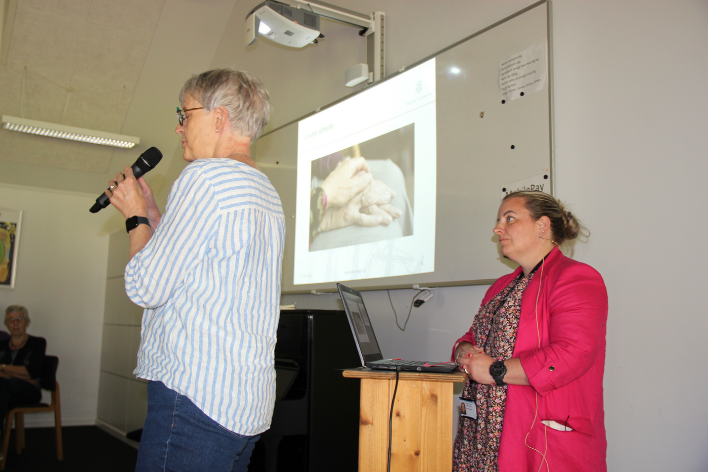 To kvinder leder en præsentation, den ene taler i en mikrofon.