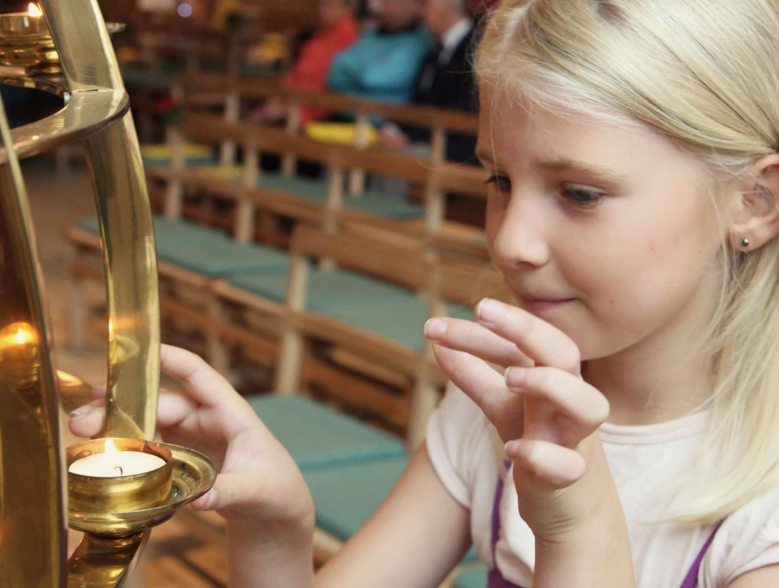 Ung pige tænder et lys i kirken.